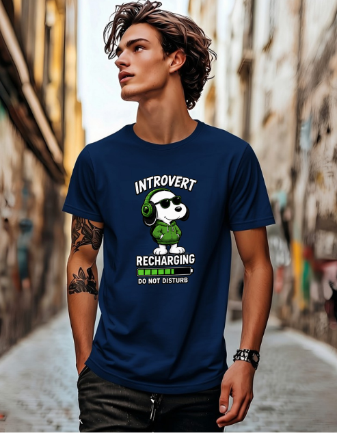 A man wearing a navy blue graphic t-shirt with a cartoon panda wearing green headphones and the text 'INTROVERT RECHARGING DO NOT DISTURB'. The man is standing in a narrow, urban alleyway.
