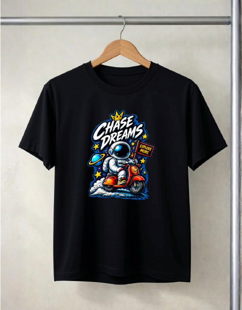 A black short-sleeve t-shirt hanging on a wooden hanger against a light beige wall. The shirt features a colorful retro graphic of an astronaut riding a red scooter with the text 'Chase Dreams' in stylized white and blue lettering.