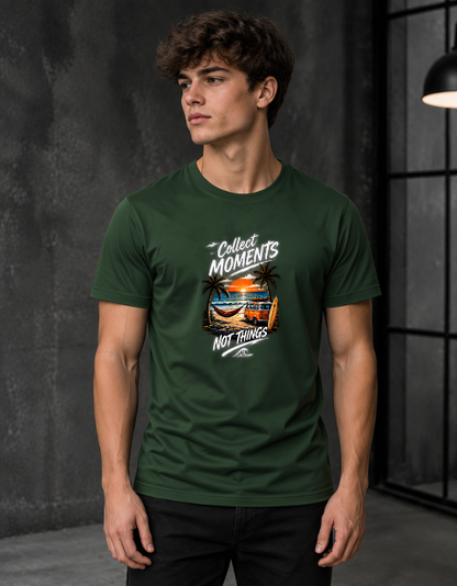 A man wearing a Bottle green crewneck t-shirt with a graphic print that reads 'Collect Moments NOT Things' around a beach scene, set against a dark gray textured studio background.