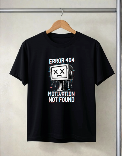 A black short-sleeve t-shirt hanging on a wooden hanger against a light beige wall. The shirt features a white and red graphic of a dripping TV with an X for a face, with the text 'ERROR 404' above and 'MOTIVATION NOT FOUND' below.