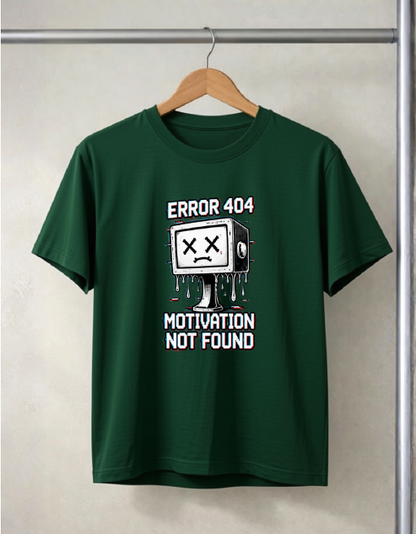 A bottle green short-sleeve t-shirt hanging on a wooden hanger against a light gray wall. The shirt features a white and black graphic of a melting computer monitor with 'ERROR 404' above it and 'MOTIVATION NOT FOUND' below it.