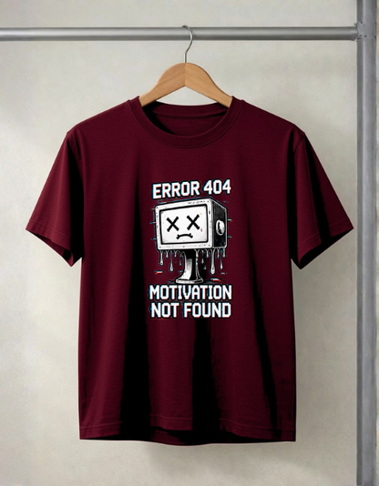 A maroon short-sleeve t-shirt hanging on a wooden hanger against a light gray wall. The shirt features a white graphic of a dripping computer monitor with an 'X' for a face, with the text 'ERROR 404' above and 'MOTIVATION NOT FOUND' below.