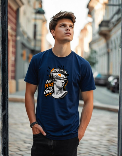 A man wearing a navy blue graphic t-shirt with a 'Find Peace in the Chaos' design, standing on a cobblestone street.