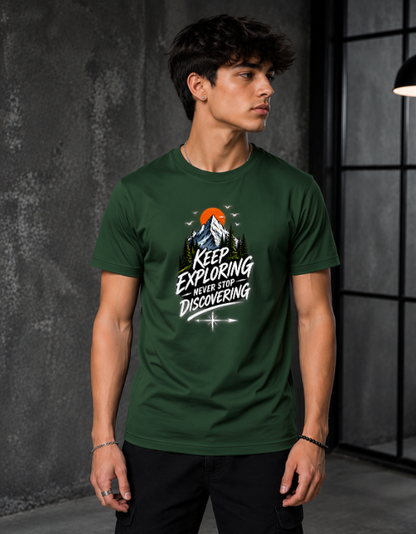 A man wearing a dark green graphic t-shirt with a mountain and sunset design and the text 'KEEP EXPLORING WHEN YOU'RE DISCOVERING'.