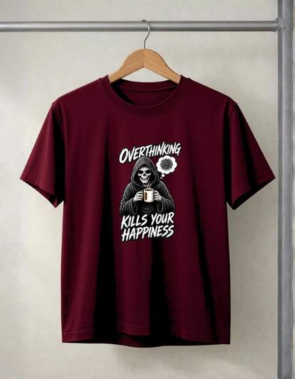 A maroon short-sleeve t-shirt hanging on a wooden hanger against a light gray wall. The shirt features a graphic of a skeleton in a black hoodie holding a mug, with the text 'OVERTHINKING KILLS YOUR HAPPINESS' in white.