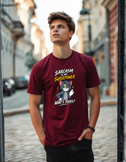 A man wearing a maroon graphic t-shirt with a cartoon cat design and the text 'SARCASM IS MY SUPERPOWER WHAT'S YOURS?' standing on a cobblestone street.