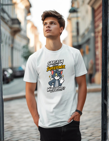 A young man wearing a white graphic t-shirt featuring a cartoon cat character and the text 'SARCASM IS MY SUPERPOWER WHAT'S YOURS?' standing in an outdoor street setting.