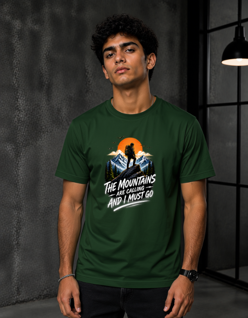 A man wearing a Bottle Green short-sleeve graphic t-shirt with a mountain and sunset design and the text 'THE MOUNTAINS ARE GORGING AND I MUST GO'.