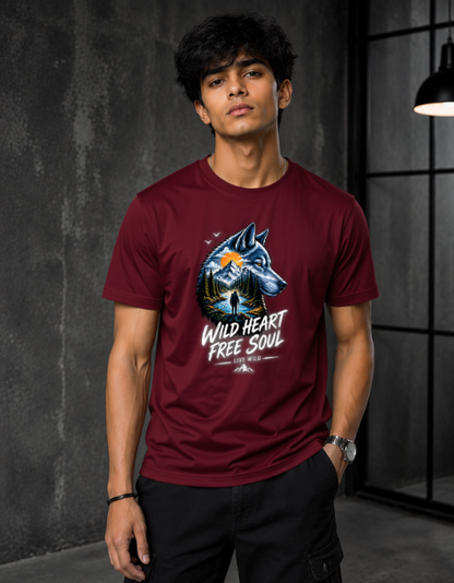 A man wearing a maroon crewneck t-shirt with a graphic of a wolf and the text 'WILD HEART FREE SOUL' in a dark industrial room setting.